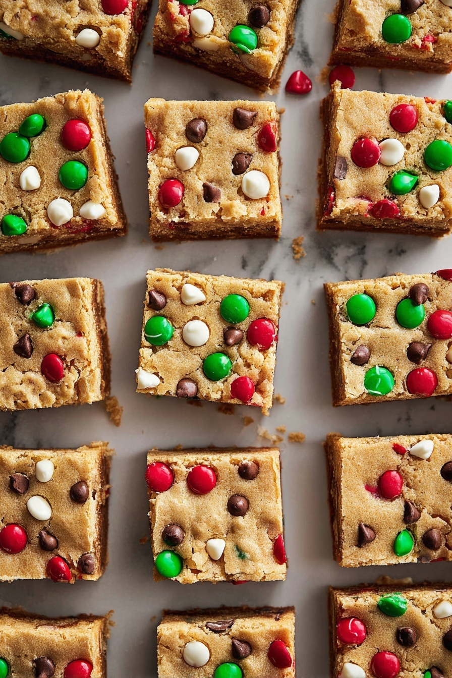 The image shows many square bars arranged in a neat grid on a white marbled surface. Each bar has two visible layers: the bottom is a darker brown, dense layer, and the top is a lighter golden-brown cookie-like layer with a slightly cracked texture. Scattered on the top are colorful red and green candy pieces, white chips, and small dark chocolate chips, creating a festive and textured look across all the bars. The bars vary slightly in size but keep a uniform thickness, with the candies and chips embedded in the cookie layer. photo taken with an iphone --ar 2:3 --v 7